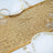 Gold sequin table runner with elegant plates and glasses for festive dining decor.