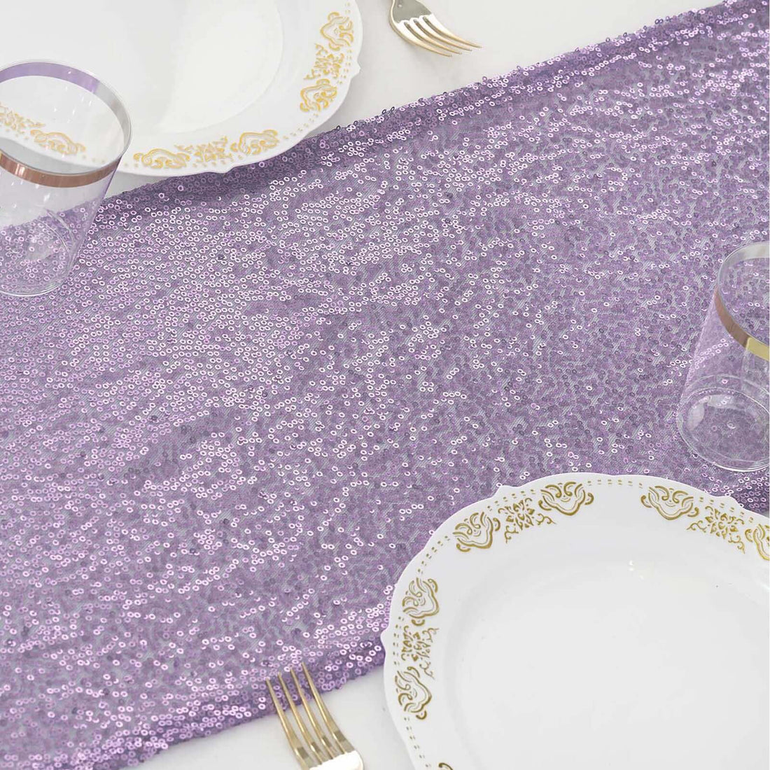 Purple sequin table runner with elegant dinnerware and glasses.