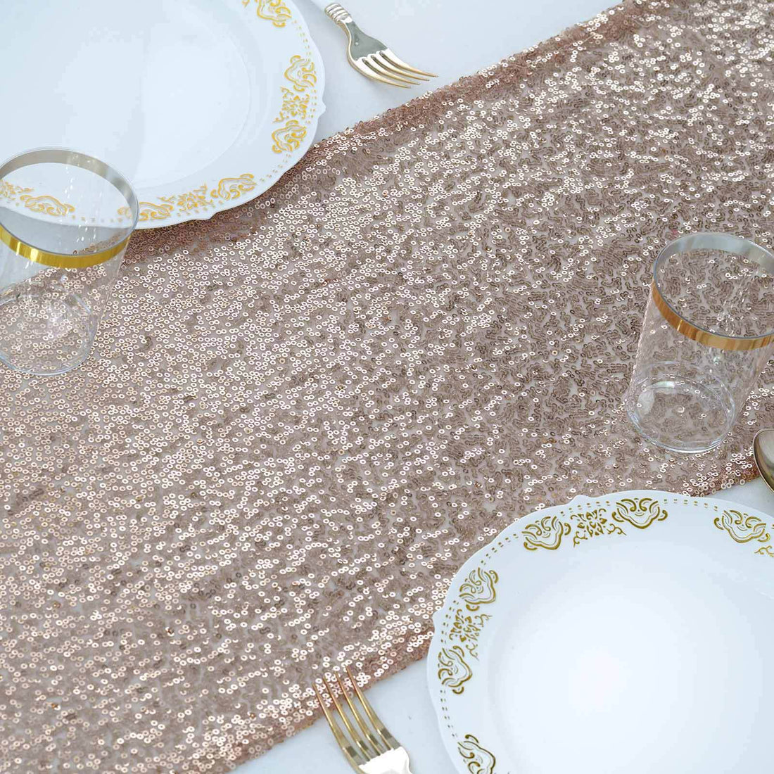 Rose gold sequin table runner with elegant dinnerware set.