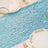 Blue sequin table runner on a dining table with elegant plates and glasses.