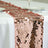 Rose gold sequin table runner on a white tablecloth.