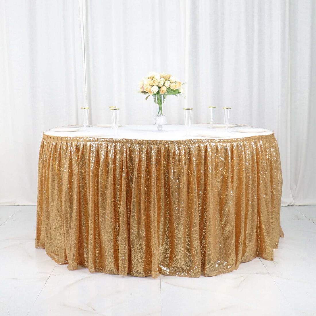 Gold sequin table skirt with elegant floral centerpiece.