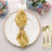 Elegant gold and yellow napkin with a decorative ring on a plate, surrounded by flowers.