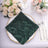 Elegant green embroidered napkin on a decorative plate with flowers and tableware.