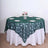 Green leaf-patterned tablecloth on a round table set for dining.