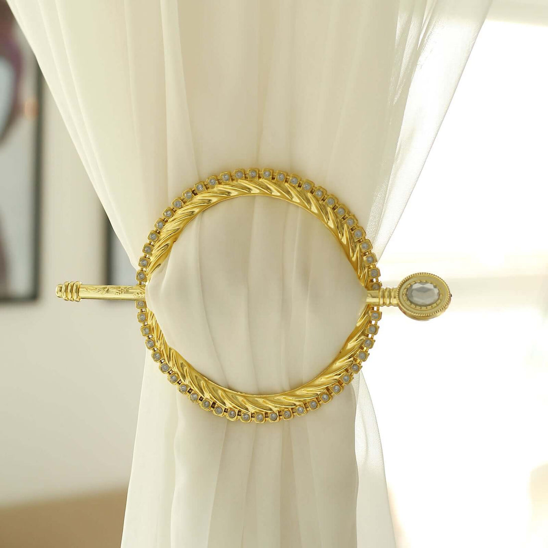 Gold curtain tieback with decorative details on a white curtain.