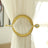 Gold curtain tieback with decorative details on a white curtain.