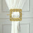 Gold decorative curtain tieback with ornate design and crystal accents.