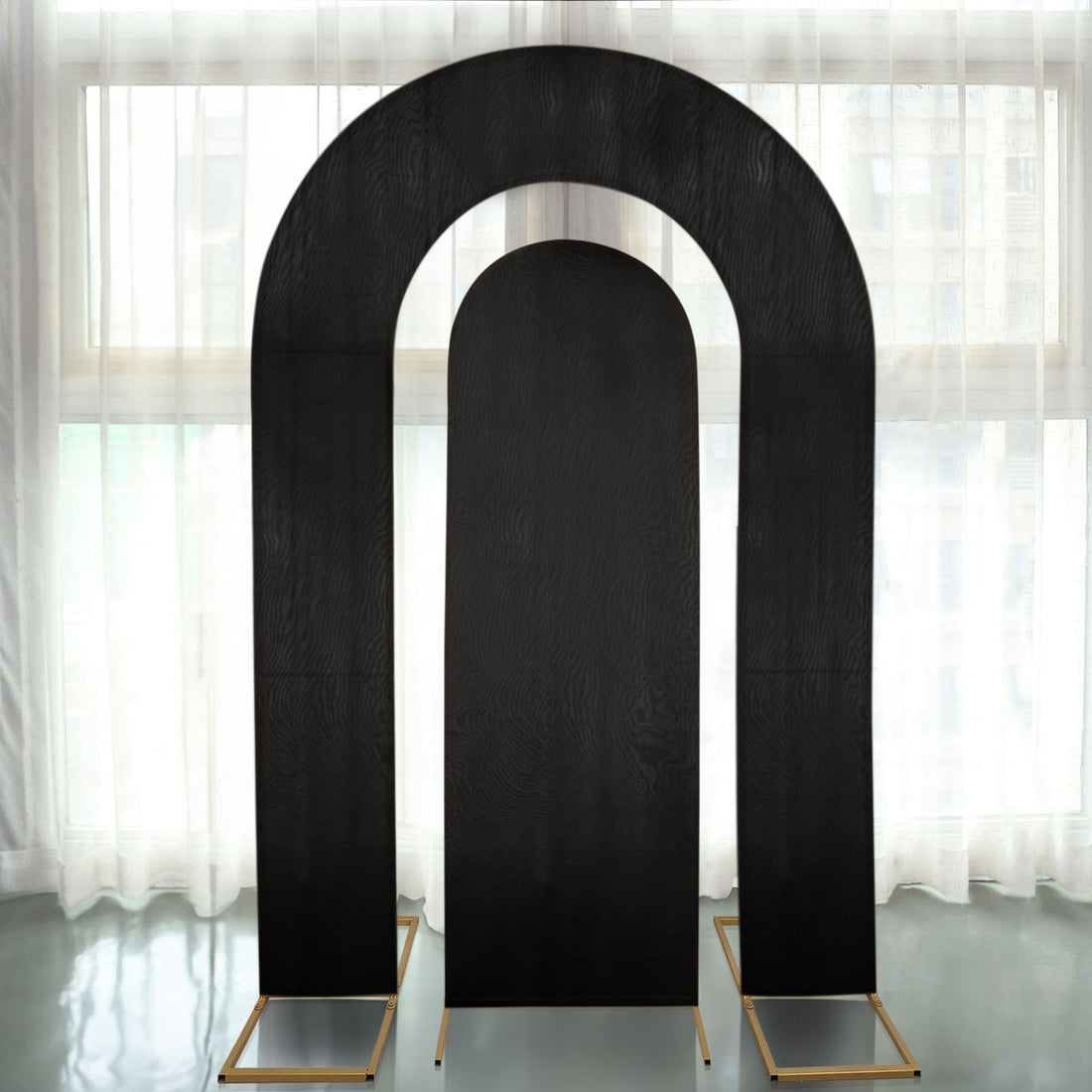 Black arch backdrop with gold stands for events and photography.