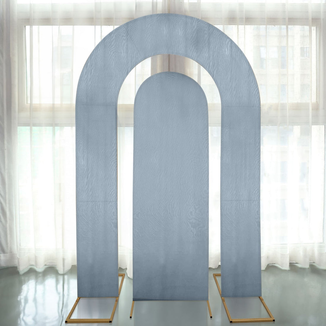 Gray arch backdrop with gold stands in a bright, airy space.