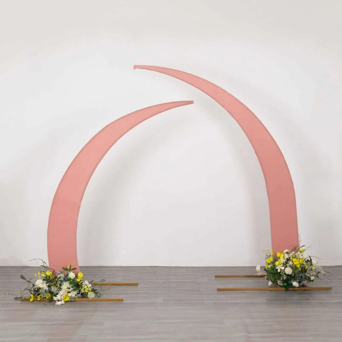 Pink curved arch with floral arrangements at the base