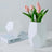 Geometric white vase with pink tulips on a coffee table