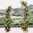 Floral archway display with pink and yellow roses in outdoor setting.