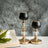 Elegant black and gold candle holders with crystal accents beside a book and flowers.
