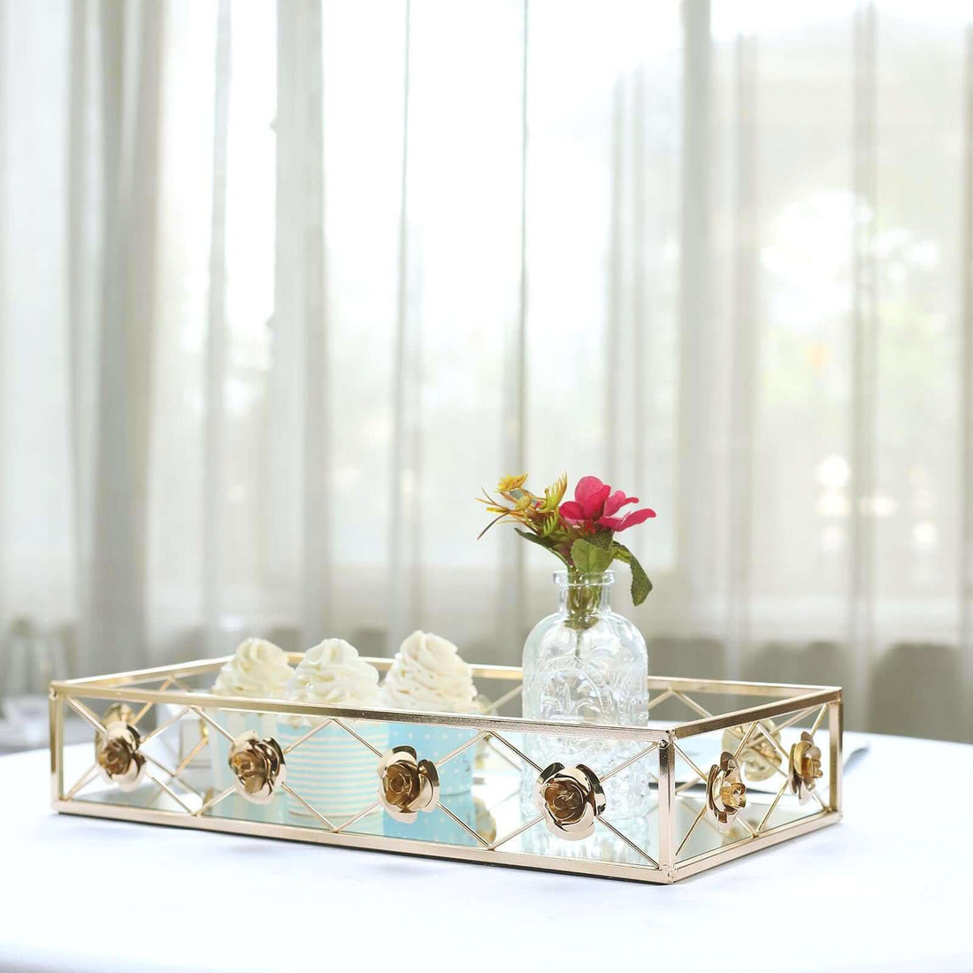 Elegant gold tray with flowers and dessert against a soft, airy background.