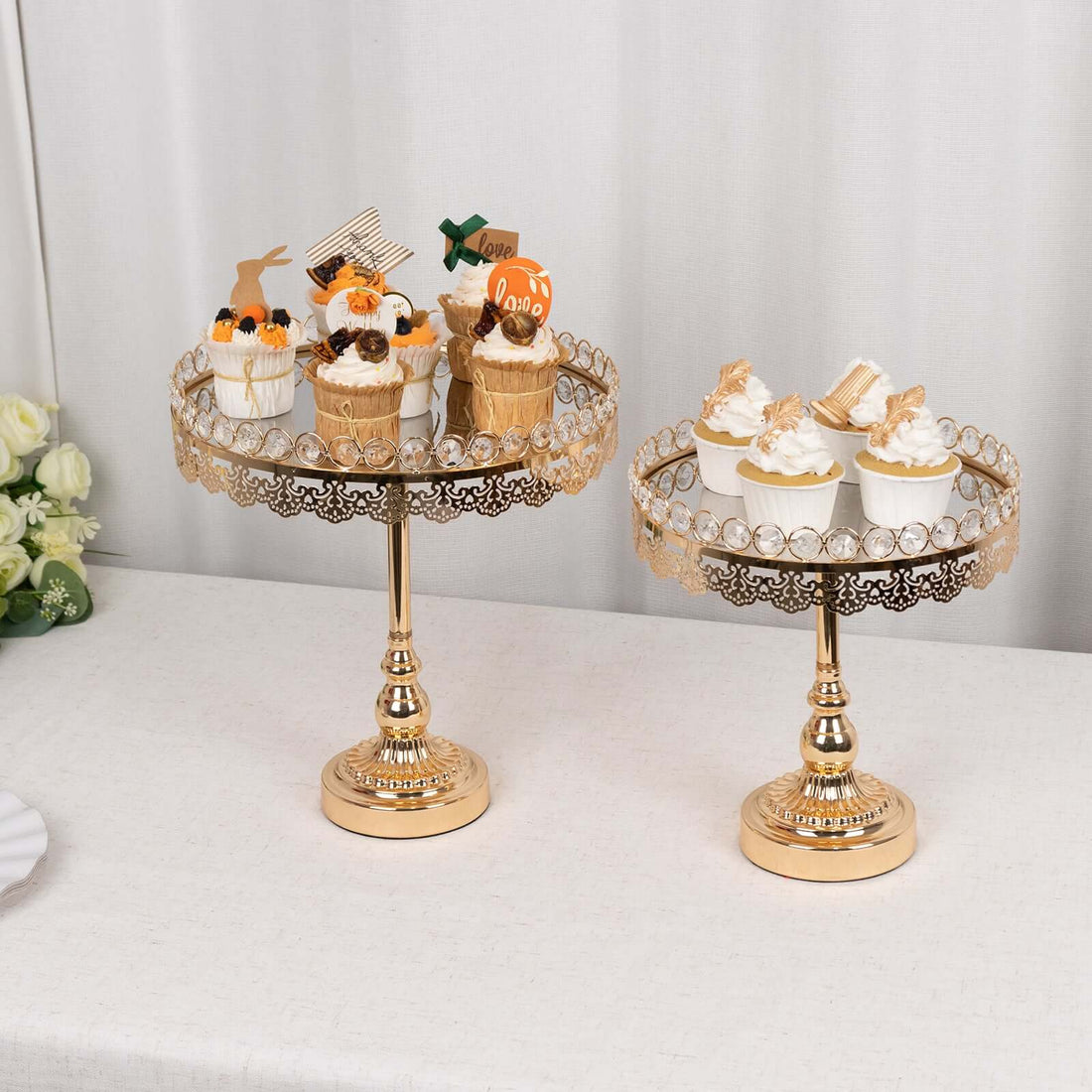 Elegant gold cupcake stands with decorated desserts on a table.