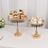 Elegant gold cupcake stands with decorated desserts on a table.