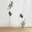 Gold floral arch with white roses and greenery on a plain backdrop.