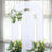 White floral arch backdrop with greenery and flowers for events or photography.