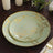 Elegant green dinner plates with gold floral design, arranged on a wooden table.