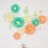 Colorful paper flowers arranged in a heart shape with decorative leaves and butterflies.