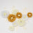 Assorted paper flowers in white, yellow, and gold on a white background.