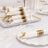 Elegant white napkins with gold cutlery, beautifully arranged on a table setting.