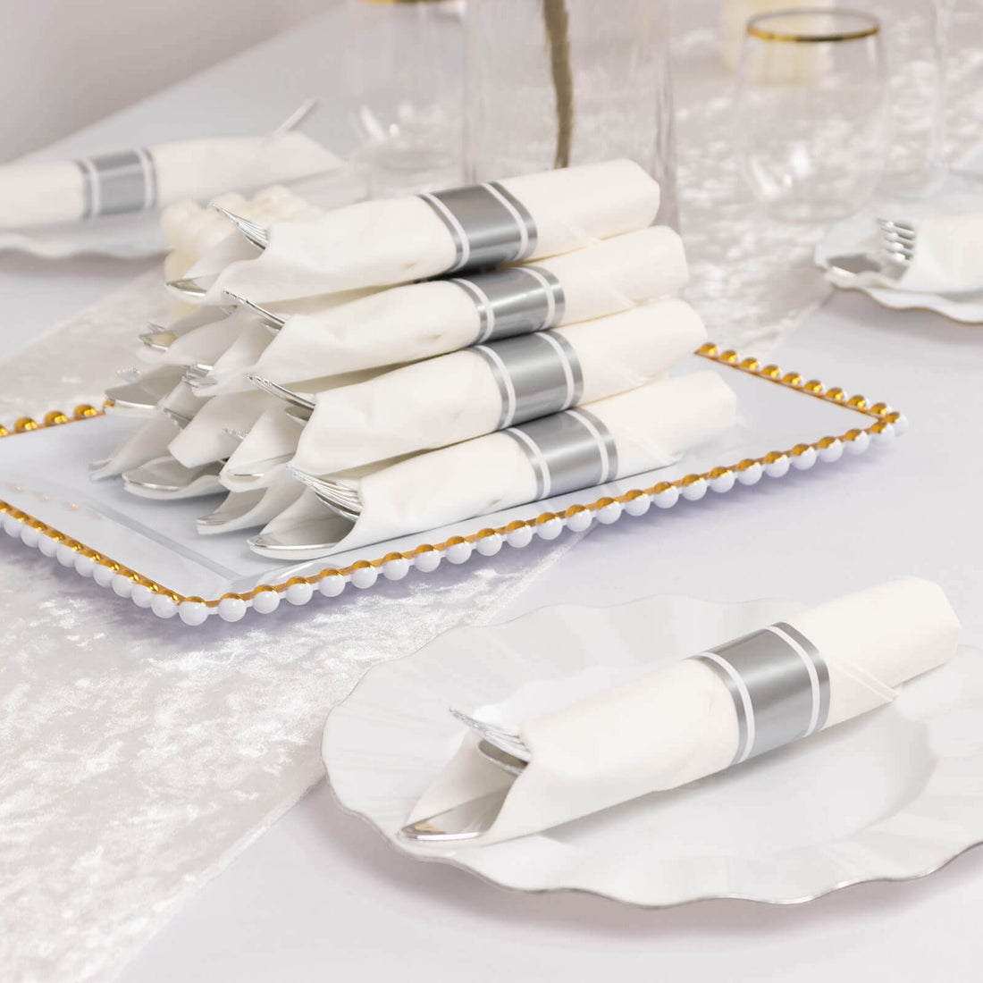 Elegant white napkins with silver accents arranged on a decorative plate.