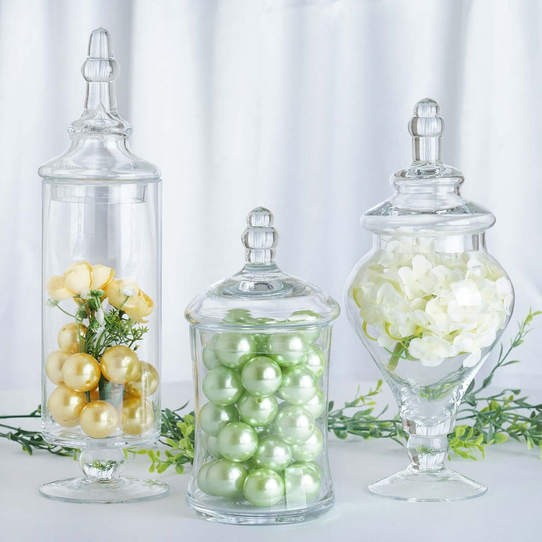 Glass apothecary jars with decorative fillers in various sizes and colors.