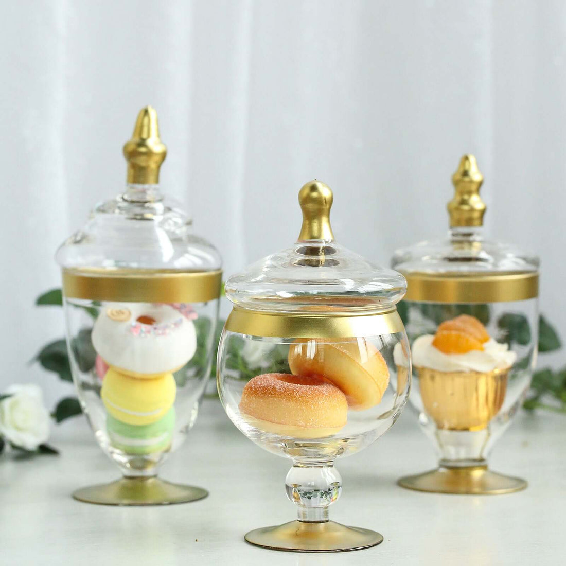 Decorative glass jars with gold accents holding colorful treats and donuts.