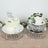 Elegant birthday cakes on mirrored stands with floral decorations.