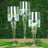 Elegant glass candle holders with flowers and water, set against a green backdrop.