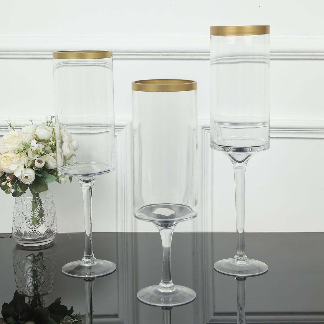 Elegant glass vases with gold rims on a reflective surface.