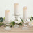 Elegant glass candle holders with white candles, surrounded by greenery.