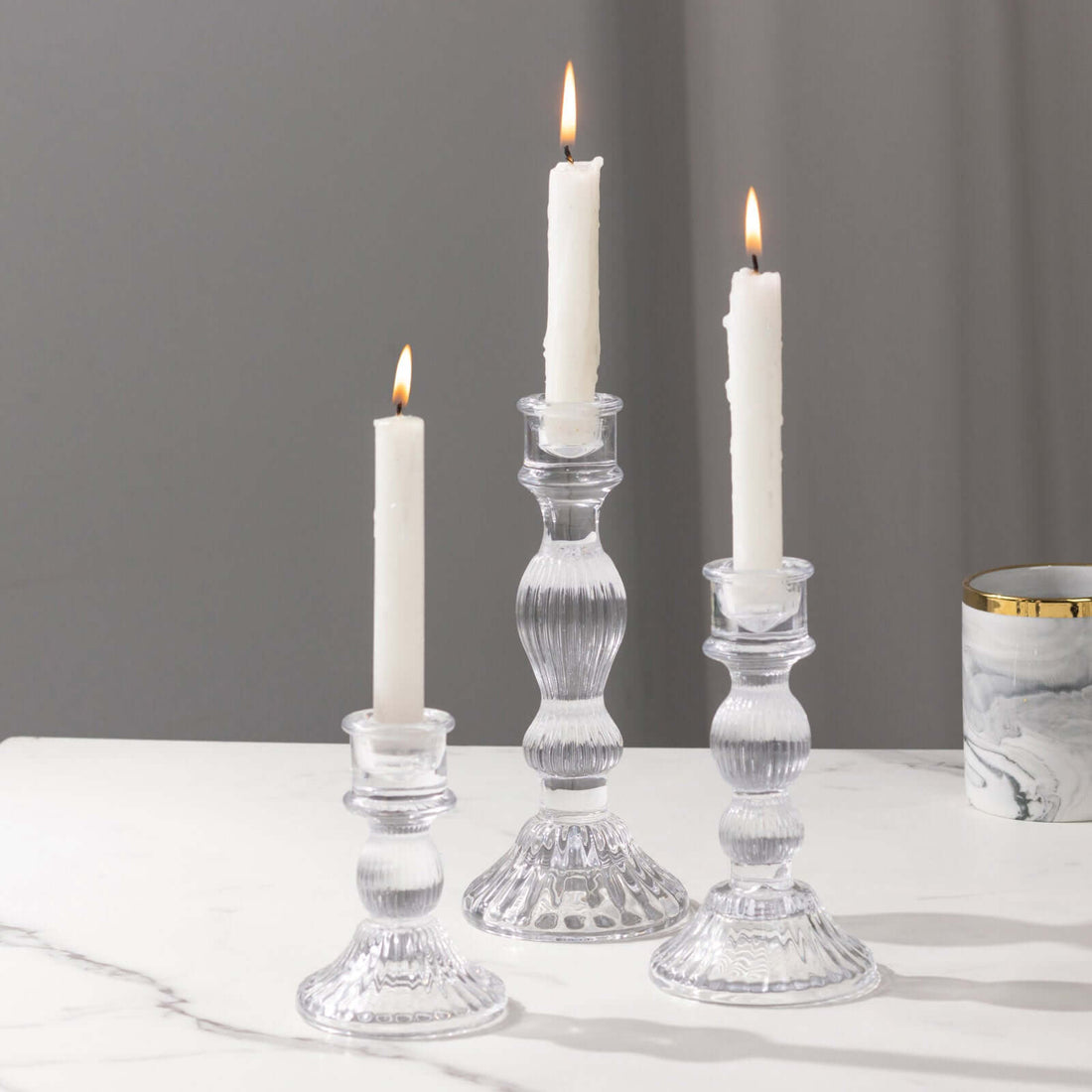 Elegant clear glass candle holders with white candles lit.