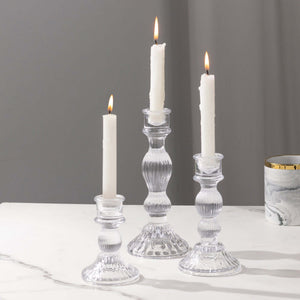 Elegant clear glass candle holders with white candles lit.