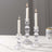 Elegant clear glass candle holders with white candles lit.