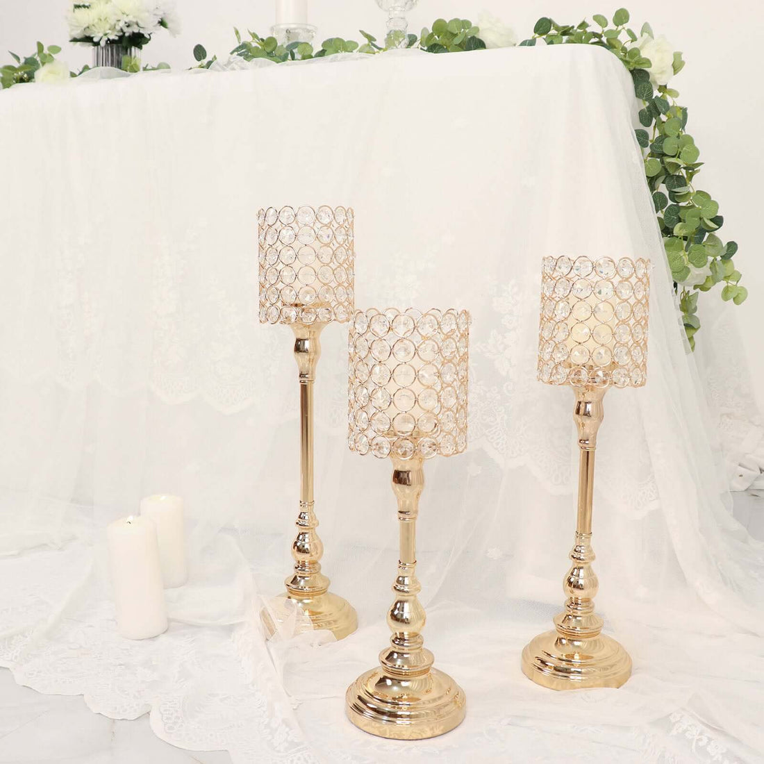 Elegant gold candle holders with crystal accents on a white table setting.