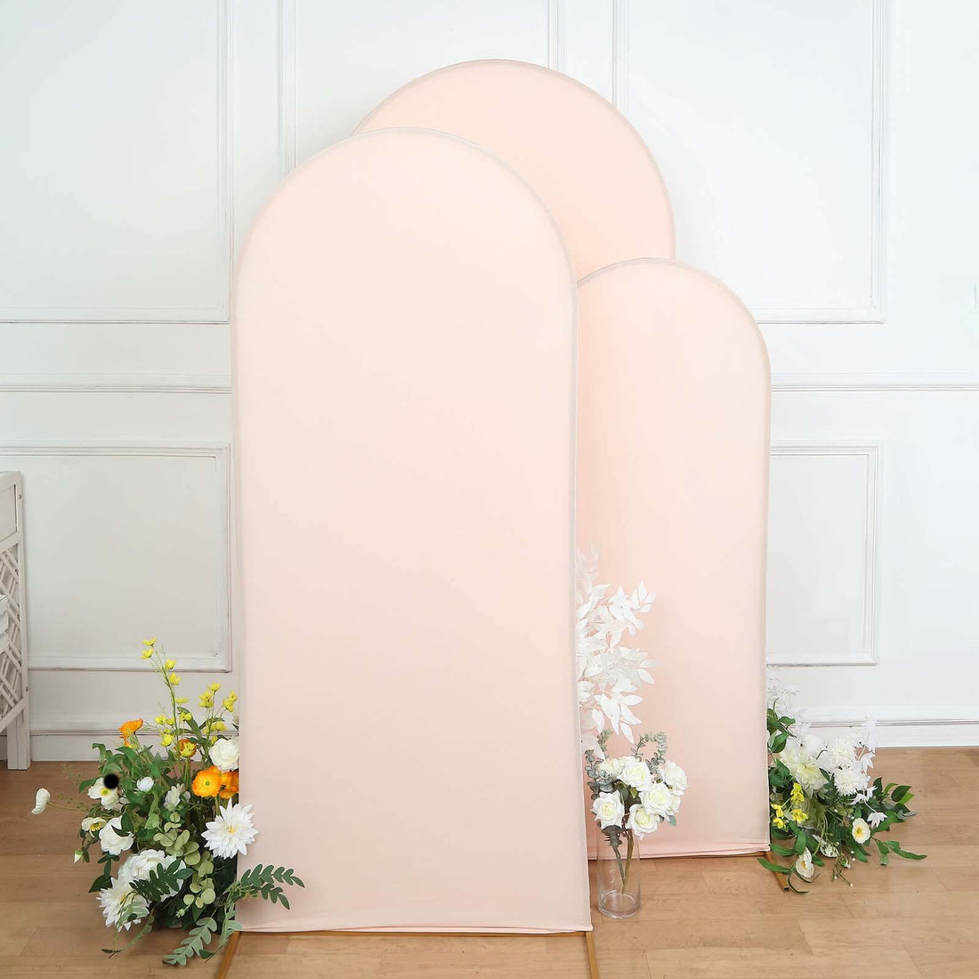Three pink fabric backdrops with floral arrangements on the floor.