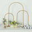 Gold arch backdrop stand with flowers arranged on a table.
