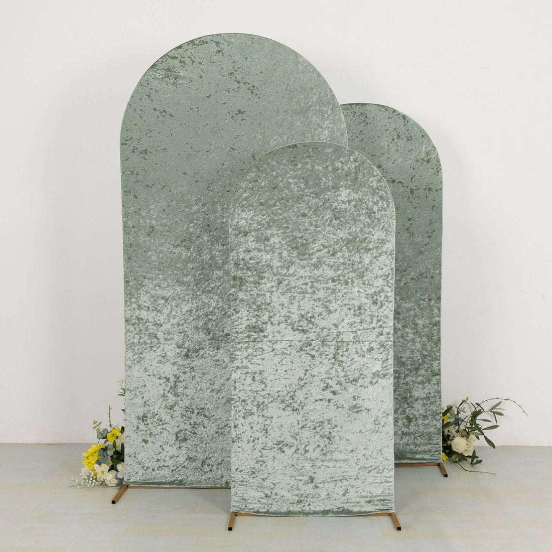 Three textured green backdrops with arch shapes, styled with flowers at the base.