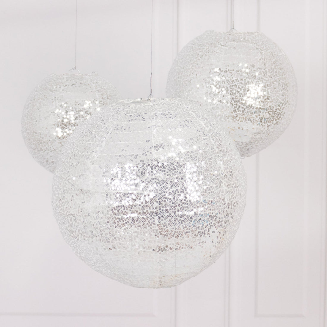Silver decorative paper lanterns hanging in a bright setting.