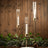 Elegant candle holders with glass tubes and gold accents, styled with greenery.