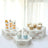 Assorted desserts on hexagonal wooden stands in a bright setting.
