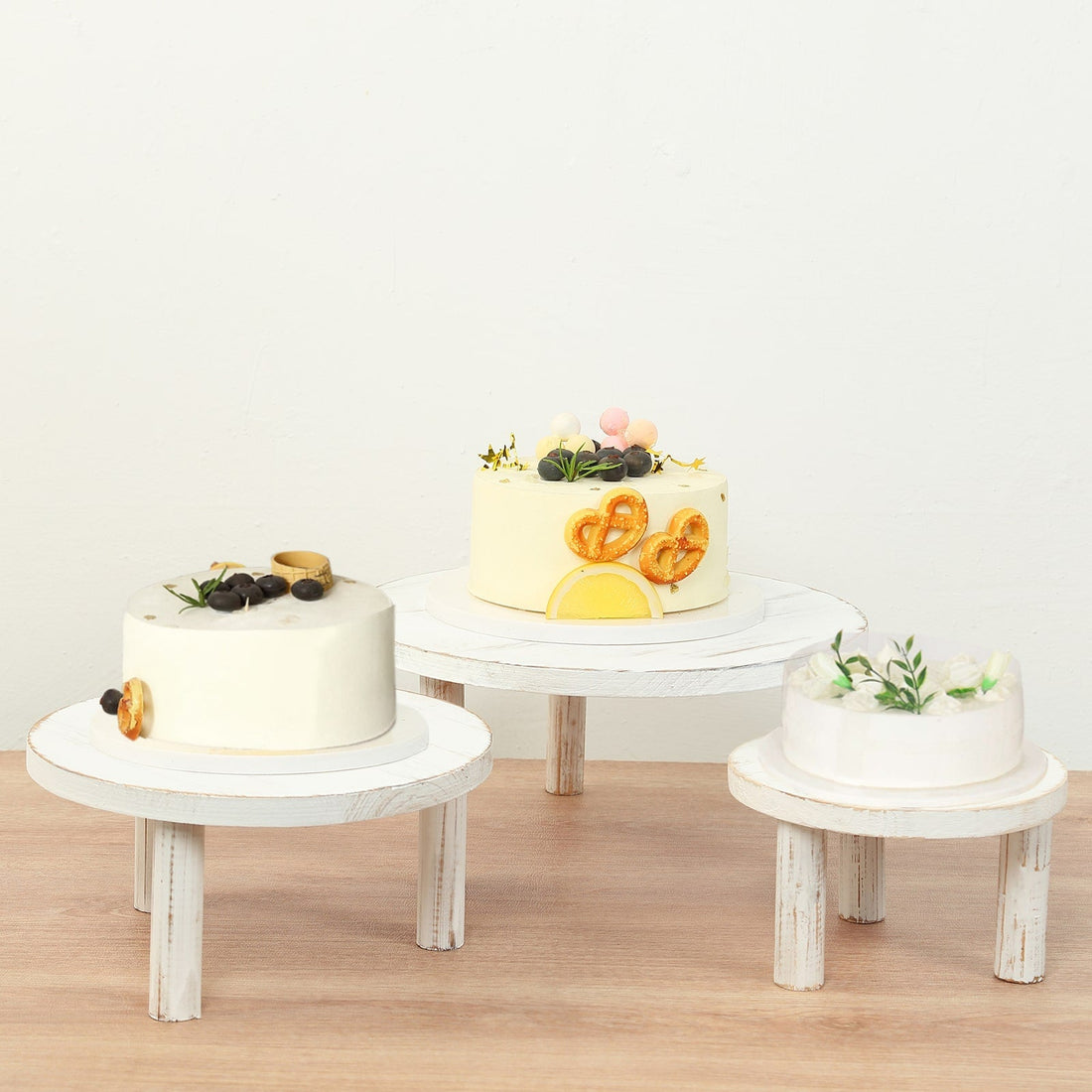 Decorative cakes on wooden stands against a light background.