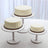 Three white frosted cakes on decorative stands.