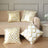 Decorative gold and white patterned throw pillows on a beige sofa.