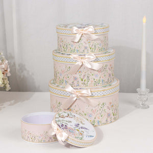 Decorative floral gift boxes with bows stacked on a table.