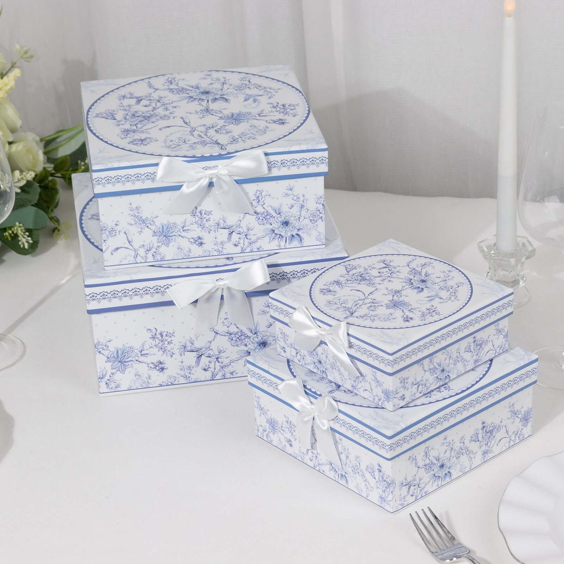 Decorative floral gift boxes with ribbons stacked on a table.