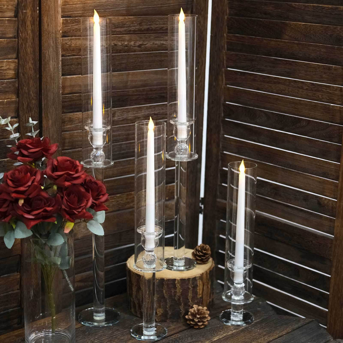 Elegant glass candle holders with LED candles and decorative flowers.